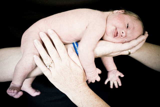 A newborn baby is being held by a person's hand.