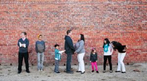 A group of people standing in front of a brick wall.