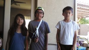 Four children standing next to each other holding tennis rackets.