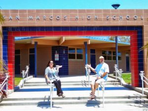 Two people standing in front of a high school entrance.