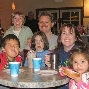 A real life family posing for a picture at a coffee shop.