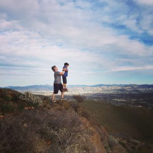 A man and a child standing on top of a mountain.