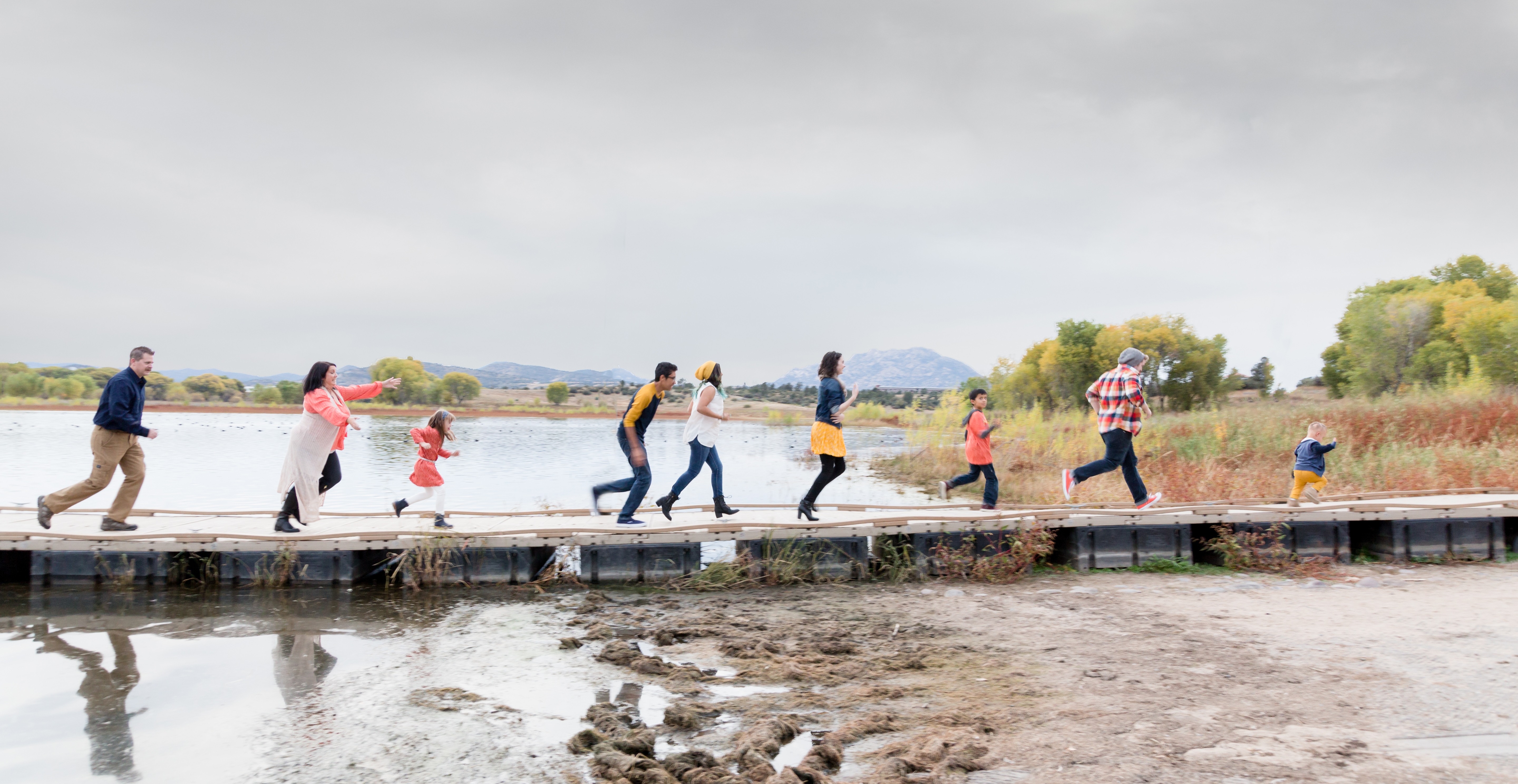 A group of people walking on a dock near a lake.