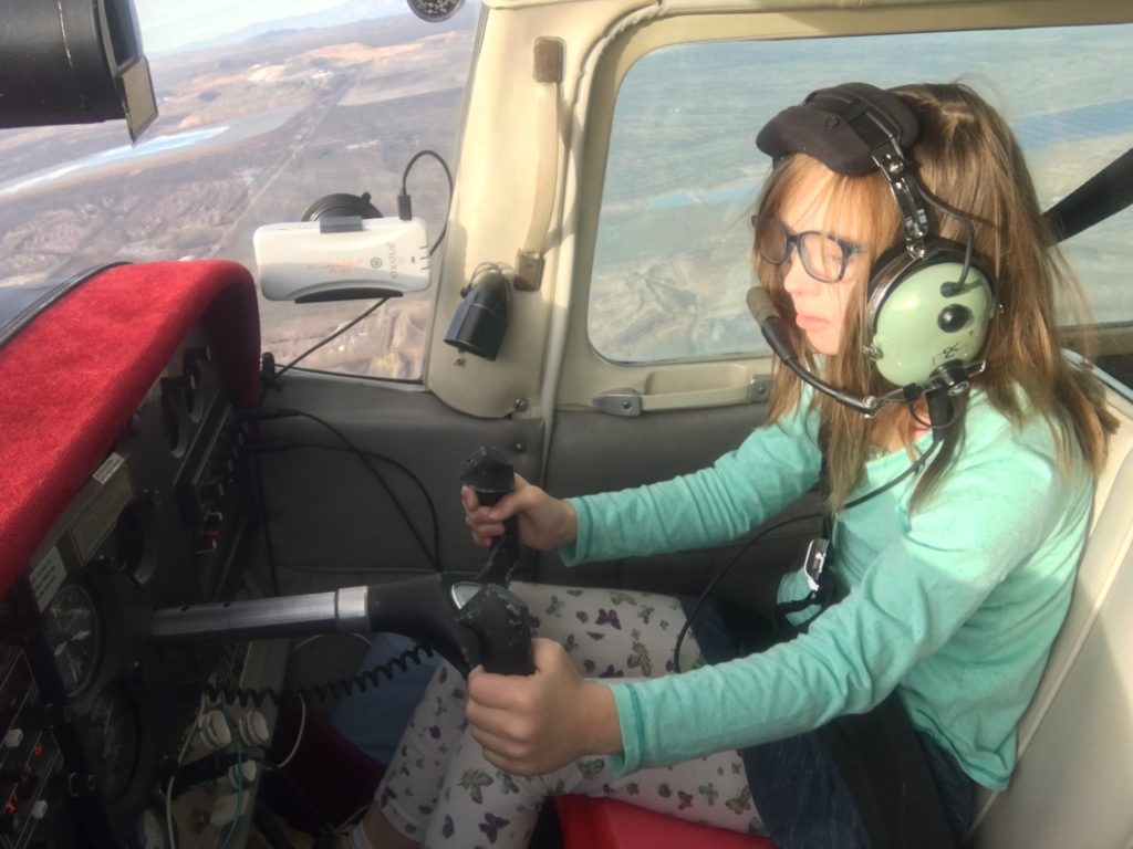 A ten year old girl with Down syndrome is at the controls of a small plane while around 6,000 feet in the air.