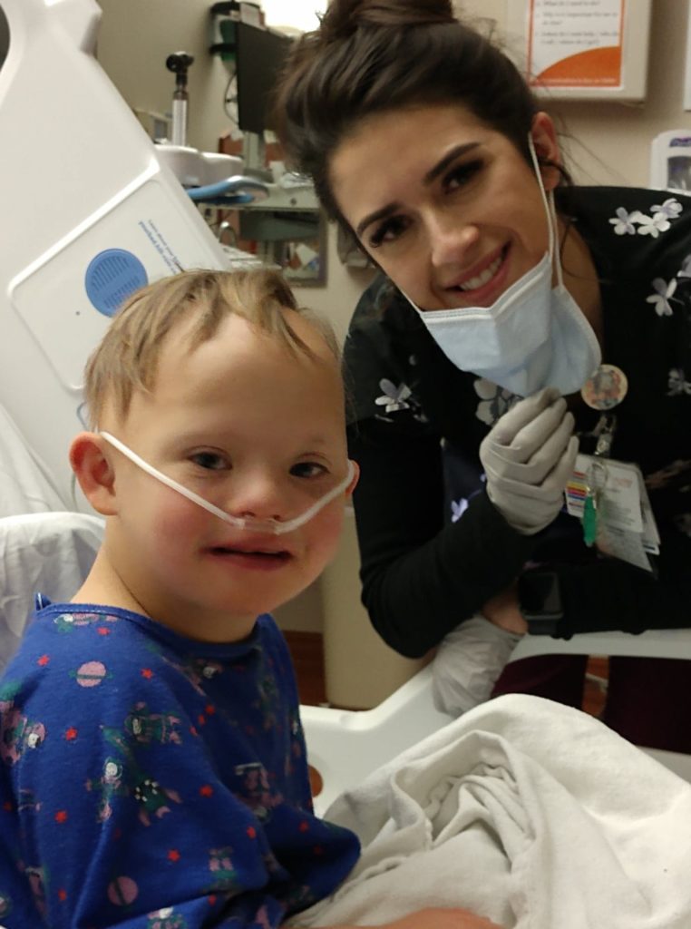 a small boy with Down Syndrome and his nurse by his bedside