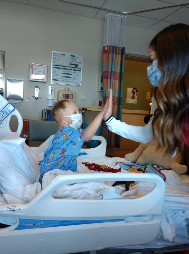 Small boy with Down syndrome wearing a hospital mask winning the heart of his nurse in the hospital