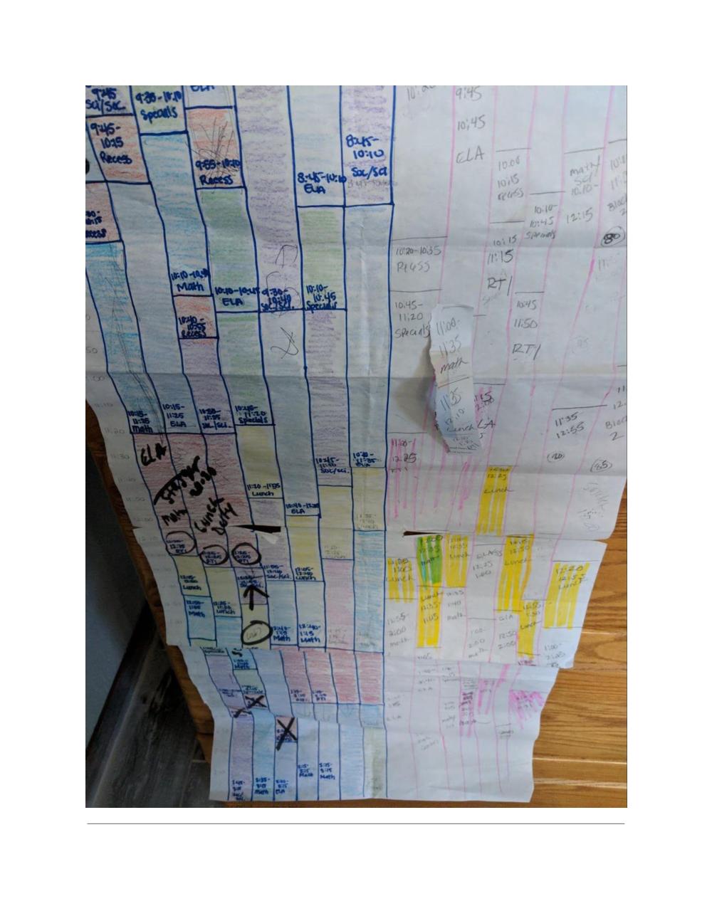 multiple sheets of paper taped together with handwritten blocks mapping out the schedules for all grades