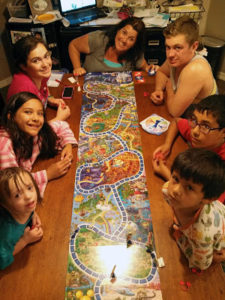 A group of people sitting around a table playing a board game.