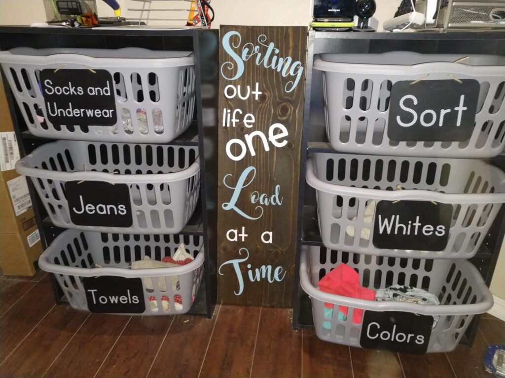 Chalkboard-labeled laundry sorter with multiple gray baskets neatly arranged on shelves for family laundry organization.