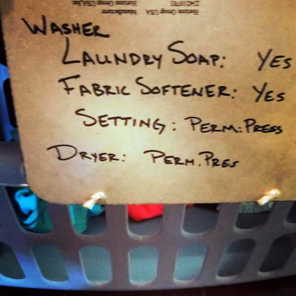 Close-up of a chalkboard laundry label listing washer and dryer settings with handwritten instructions.