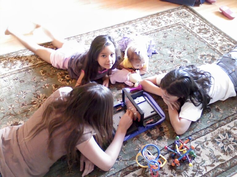 Siblings lying on the floor playing together at home, showing family connection, comfort, and stability during a season of change.