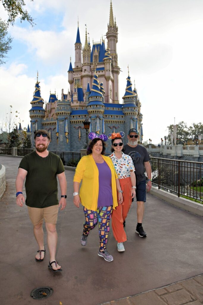 A group of adults walking together near a pink and blue fairytale castle, used in a Disney Devos reflection about joy, community, and noticing God’s goodness in everyday moments.