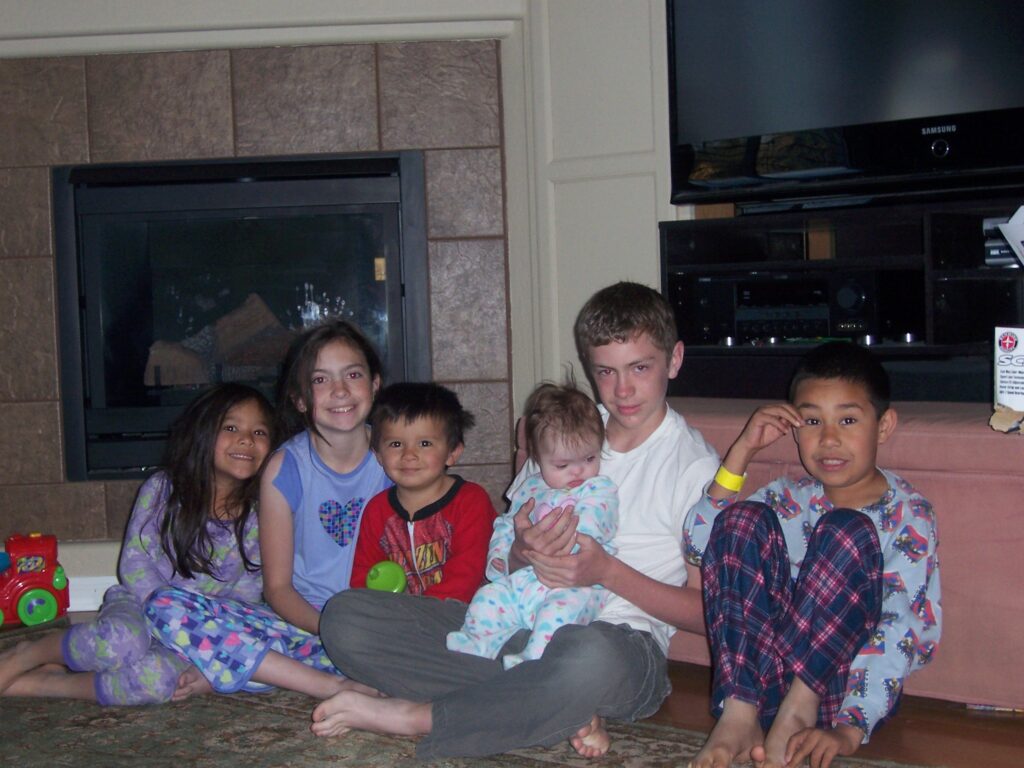 Siblings sitting together in pajamas at home, representing family, faith, and God’s provision during a season of transition.