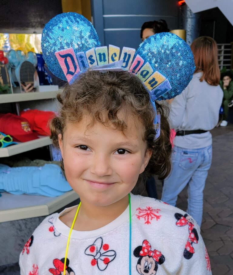 Smiling child at Disneyland wearing blue Mickey ears, capturing a sweet moment for this Disney devotion.